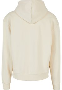 Sudadera con capucha en color crema y corte relajado. Tejido suave, puños y dobladillo de canalé. Diseño sencillo sin patrones ni acentos visibles.