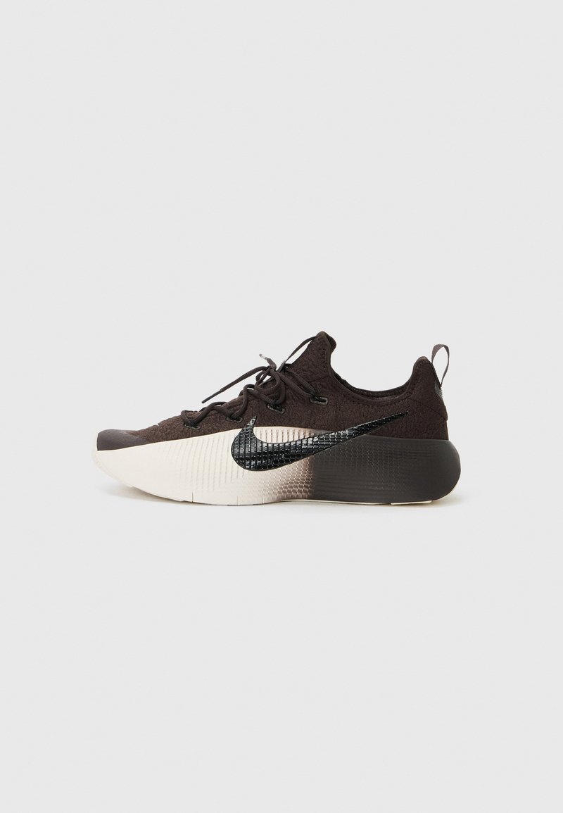 Schwarzer und grauer Nike Sportschuh mit strukturiertem Obermaterial, schwarzem Swoosh-Logo und einer weiße zu graue Farbverlaufsohle. Verfügt über ein Schnürdesign und eine Rückenschlaufe.