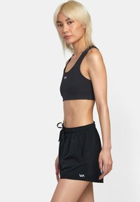 Sort atletisk sports-bra og shorts med elastisk talje og snor. Materialet ser glat ud; inkluderer et logo på brystet og låret.