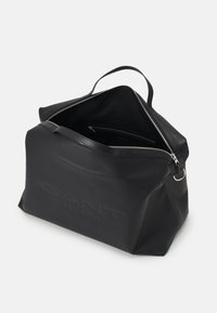 Mustassa nahkabagissa on jämäkkä muotoilu, jossa on vetoketjukiinnitys, sisäiset taskut ja yläpaino. Logo on kohopainettu etupuolelle.