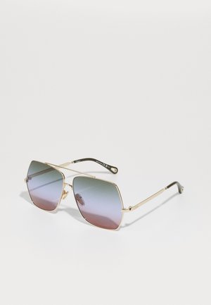 Gold metal sunglasses with large, angular frames. Lenses feature a gradient from light blue to pink. Thin arms with a logo detail.