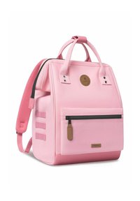 Sac à dos en toile rose de forme rectangulaire, avec une poignée supérieure, des bretelles ajustables, une poche zippée à l'avant et un patch logo circulaire.