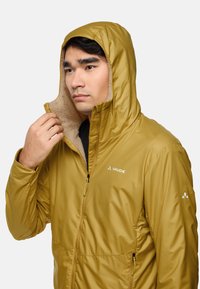 Light yellow insulated jacket with a hood, featuring a soft interior lining, front zipper, and logo accents on the chest and sleeve.