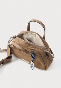 Brūna maza rokas soma ar atvērtu rāvējslēdzēju, atklājot bēšīgu iekšpusi, zilu atslēgu piekariņu ar sudraba burtiem un regulējamu šļūteni uz balta fona.