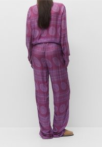 Paars gestreept co-ord set met een losse, lange mouw top en wijde broek, gemaakt van een soepele stof met ronde ontwerpen.