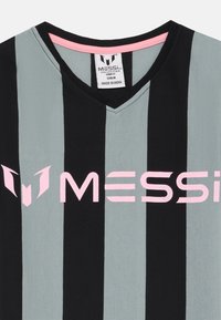 Grå og svart stripete t-skjorte med V-hals, med en rosa "MESSI" logo på framsiden. Laget i India.