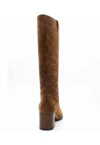 Stivale marrone in suede, alto fino al ginocchio, con punta arrotondata, tacco impilato e dettagli di cucitura minimi. Presenta una texture liscia e morbida.