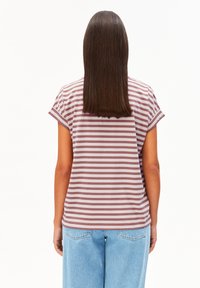 Frau mit glattem braunem Haar, die ein mauve- und weiß gestreiftes Kurzarmshirt und helle blaue Jeans trägt, und von hinten steht.