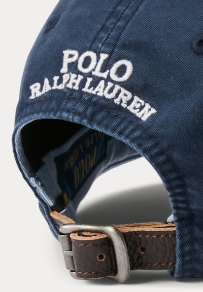 Șapcă Polo Ralph Lauren bleumarin cu logo alb brodat și curea reglabilă din piele maro cu cataramă metalică în spate.
