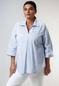 Chemise bleu clair à manches trois-quarts, ornée de fines rayures verticales et d'un col. Tissu lisse avec une coupe décontractée.