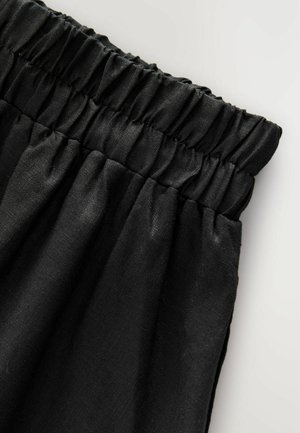 Must mustriba, millel on kogutud elastne vöökoht, omab siledat tekstuuri ja pehme viimistlusega, esitades voldid ja vabalt langevat istuvust.