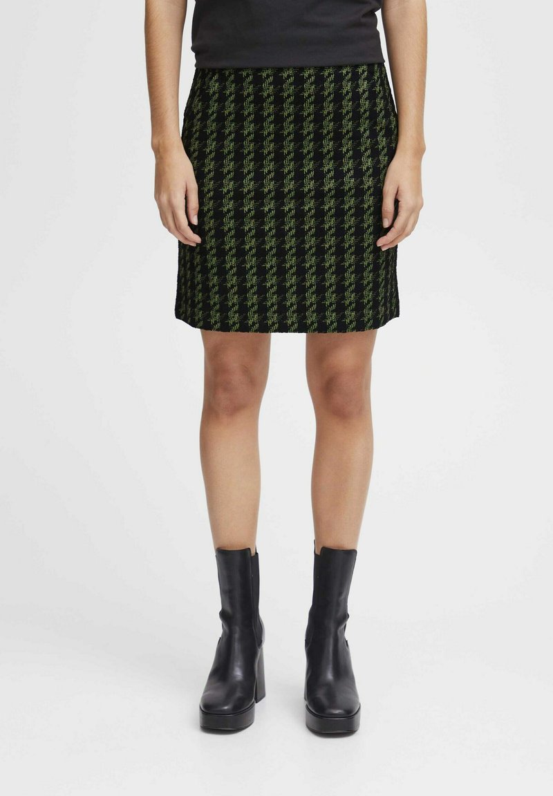 Zwart en groen gestreepte rok met een rechte snit, gekleed tot de knie, gemaakt van een gestructureerde stof. Gestyled met zwarte enkellaarzen.