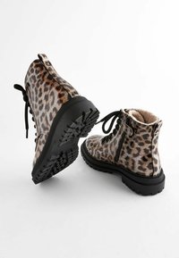 Bottes Cheville imprimé léopard avec semelle en caoutchouc noir, en matériau synthétique lisse, à lacets à l'avant et fermeture éclair sur le côté. Intérieur doublé en matériau doux.