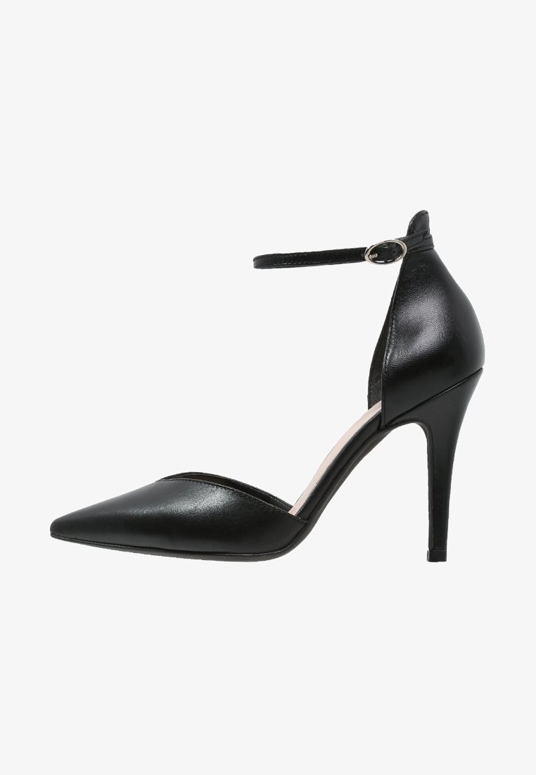 Bottines noires en cuir verni à talons hauts avec bout pointu, brides autour de la cheville et découpe sur le côté. Texture lisse, talon d'environ 10 cm.