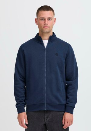 Marinblå zip-up sweatshirts med hög krage, långa ärmar och sidofickor. Har en diskret logotyp på bröstet. Tillverkad av textil med struktur.