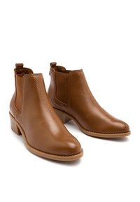 Bottes courtes en cuir marron avec une finition lisse, bout arrondi, panneaux latéraux élastiques et un petit talon bloc. Tige texturée avec coutures ton sur ton.