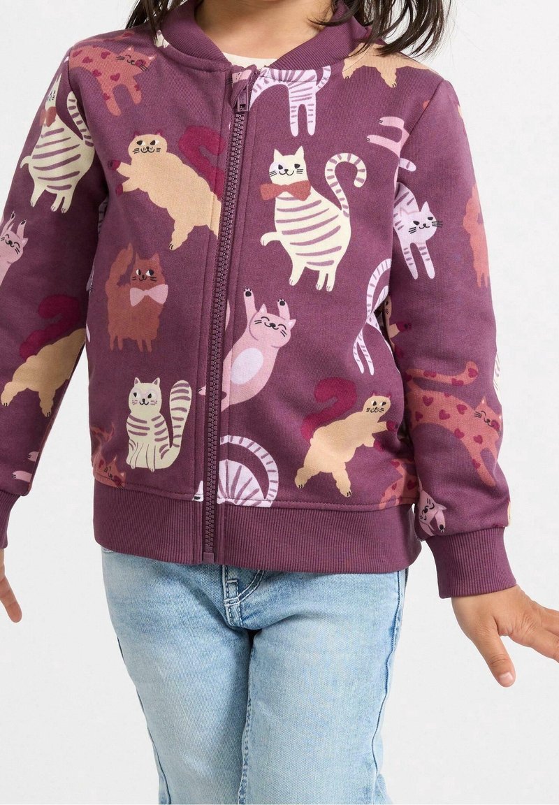 Paarse rits-trui met speelse kattenillustraties in verschillende kleuren en poses. Gemaakt van zacht materiaal met ribgebreide manchet.