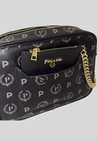 Borsa a tracolla in pelle nera con tracolla in catena dorata, dotata di una tasca frontale con zip e un motivo di loghi e corone di alloro.