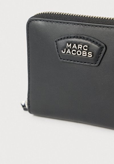 Čierna kožená peňaženka so zipsovým zatváraním, s textúrovaným povrchom a strieborným logom "Marc Jacobs" na prešitom štítku.