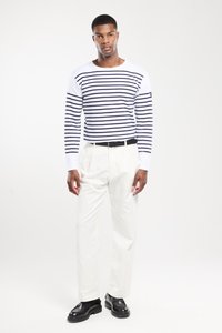 Gestreiftes Langarmshirt in Weiß und Marine, kombiniert mit weißen Hosen und schwarzen Schuhen. Verfügt über einen Rundhalsausschnitt und eine lässige Passform.