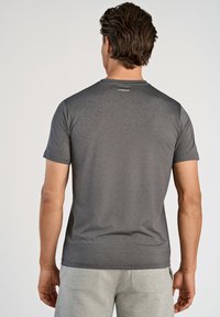 Grå t-shirt med korte ærmer, tekstureret overflade og rund halsudskæring. Har et lille logo nær halsudskæringen på bagsiden.