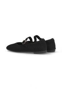 Zapatos planos de tela negra con textura ribeteada, que cuentan con dos correas ajustables y una punta redondeada. La suela es plana y suave.