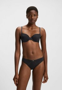 Sutiã preto e cueca combinando, feitos de um tecido suave. O sutiã possui copas moldadas com alças ajustáveis; a cueca tem um detalhe em painel transparente.