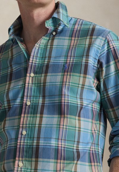 Plaid button-up shirt in light blue, green, and pink hues; features a collar, long sleeves, and small logo on the chest. Cotton material.