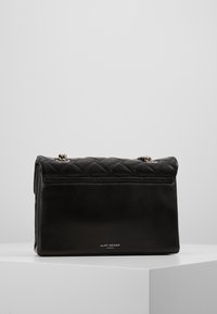 Borsa a mano in pelle nera con design a trapunto, accessori in argento e parte superiore piegata. Presenta un logo nella parte frontale inferiore.