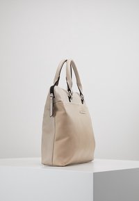 Beige Lederhandtasche mit glatter Oberfläche, ausgestattet mit zwei Griffen, einem Reißverschlussverschluss und einem Akzentpanel entlang der oberen Kante.