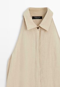 Beige ärmelloses Leinenhemd zum Knöpfen mit spitzem Kragen und einem sichtbaren Knopf, mit dem Etikett Massimo Dutti, hergestellt in Portugal.