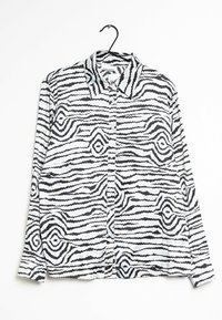 Long-sleeve, button-up shirt made of soft fabric featuring a black and white wavy striped pattern, with a pointed collar and side pockets.