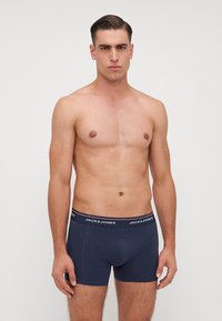 Granatowe bokserki z miękkim, elastycznym pasem, na którym widnieje nazwa marki "JACK & JONES" w białym kolorze. Gładki materiał z dopasowanym krojem.