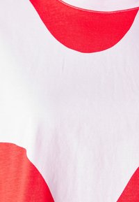 Camiseta de algodón roja y blanca con grandes formas abstractas rojas sobre un fondo blanco, textura suave y cuello acanalado.