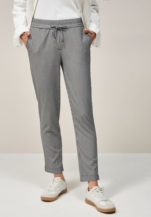 Pantaloni a righe in bianco e nero, realizzati in tessuto morbido, con vita regolabile tramite cordoncino, tasche laterali e gambe affusolate.