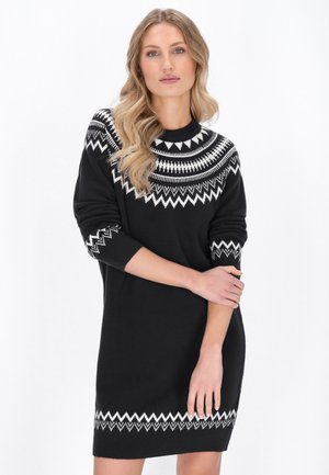 Abito nero a maglia con un motivo geometrico bianco sul colletto e sui polsini, maniche lunghe e una silhouette aderente che termina sopra il ginocchio.