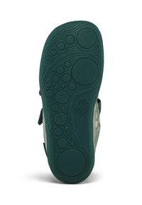 Semelle de chaussure verte pour tout-petit avec des motifs circulaires texturés conçus pour l'adhérence et la stabilité.