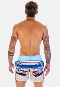 Costumi da bagno da uomo con una vita azzurro chiaro, strisce multicolori e una stampa fotografica di barche su una spiaggia sul retro.