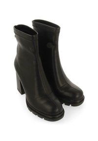 Botines negros de cuero suave con tacón de bloque, que presentan un diseño elegante y cierre con cremallera en la parte posterior.
