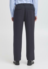 Marineblauwe dresspants met een rechte pasvorm, met een gladde textuur, twee achterzakken en een tailleband met riemlussen.