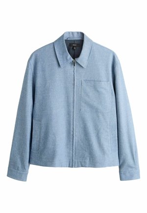 Világoskék cipzáras dzseki hegyes gallérral, hosszú ujjakkal, mellkasi és oldalsó zsebekkel, fehér háttéren.