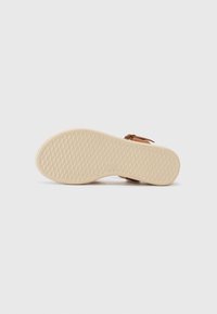 Sandal in cuoio marrone con tomaia in pelle beige a texture, cinturino regolabile e suola in gomma leggera e con motivo. Design flat, stile casual.