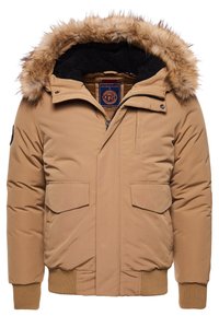 Chaqueta inflable marrón con capucha de pelaje sintético, cremallera frontal, dos grandes bolsillos con solapa, puños y dobladillo acanalados, y un suave forro interior.