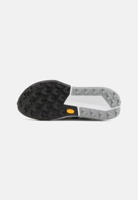 Black and gray shoe sole with a textured surface, featuring prominent grip patterns, a yellow logo, and a white midsole section.