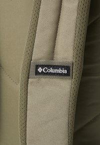 Columbia product featuring textured green fabric, mesh accents, and a black logo patch on the strap. Design emphasizes durability and lightweight comfort.