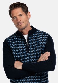 Marineblauw en blauw gestreepte ritstrui met kraag, met een houndstooth ontwerp aan de voorkant en effen kleur mouwen. Zachte textuur.