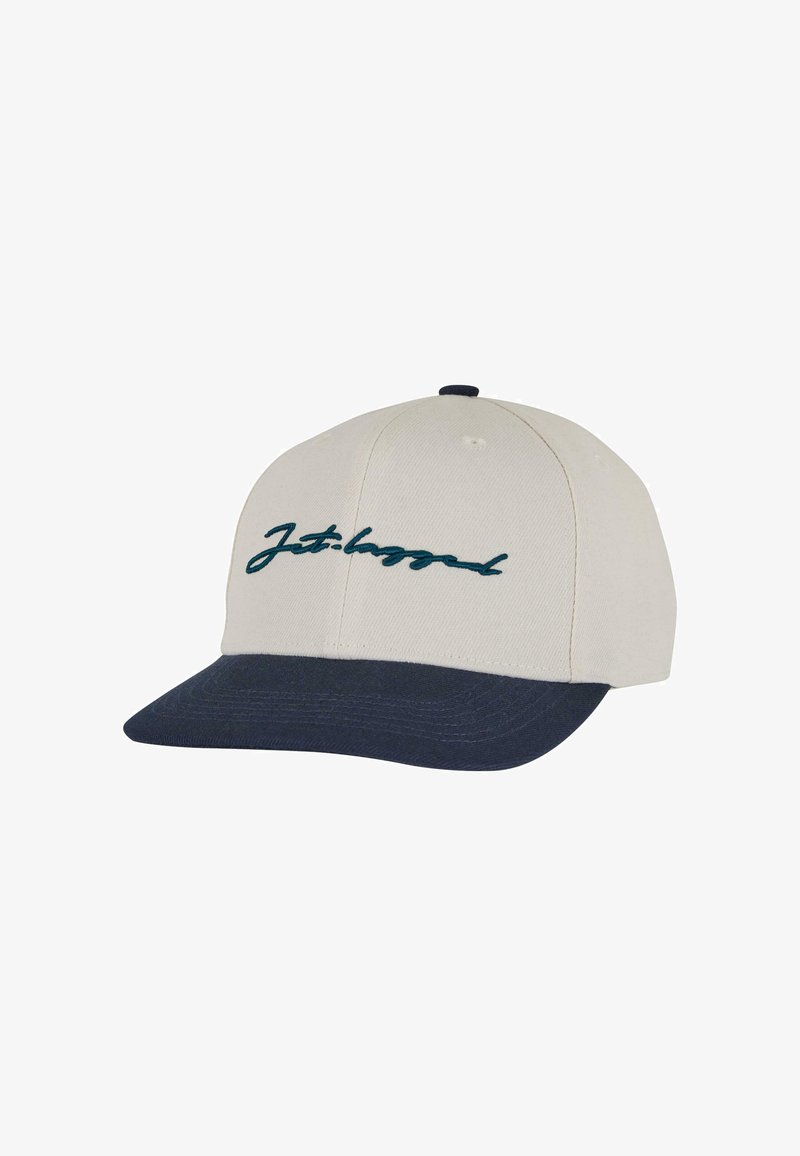 Baseballmütze mit einem beige farbenen Stoffschirm, dunklem blauen Visier und türkisfarbenem, gesticktem, geschwungenem Text "Jet-lagged" auf der Vorderseite.