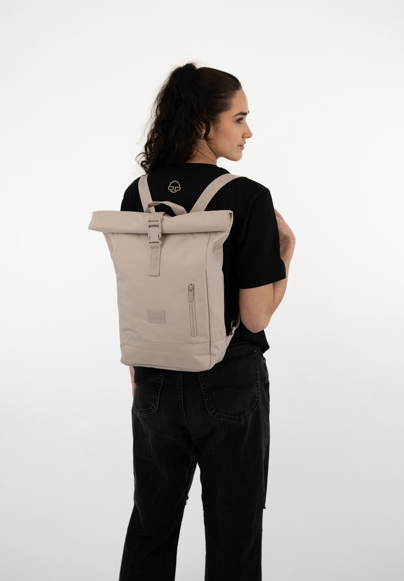 Beige roll-top backpack with adjustable straps, zip pocket, and logo detail. Made from durable fabric, features a clean, minimalist design.