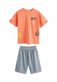 Orange bomullströja med grafiska tryck, text och gula accenter, tillsammans med ljusgrå shorts med elastisk midja.