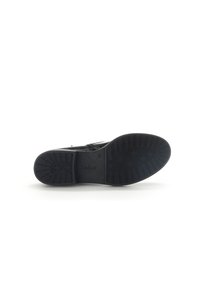 Chaussure noire avec une semelle en caoutchouc texturé. Présente un dessus lisse avec des accents subtils et un design profil bas. Logo de la marque embossé sur la semelle.